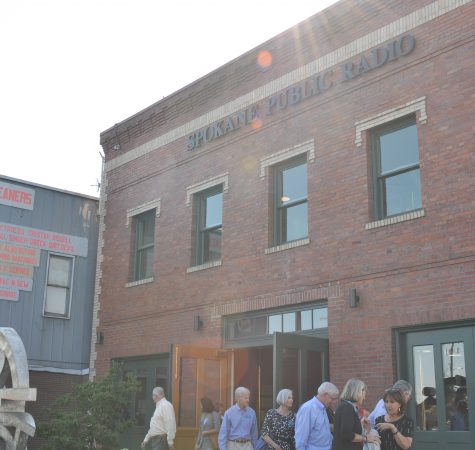 A group of people outside a red brick building that says "Spokane Public Radio."