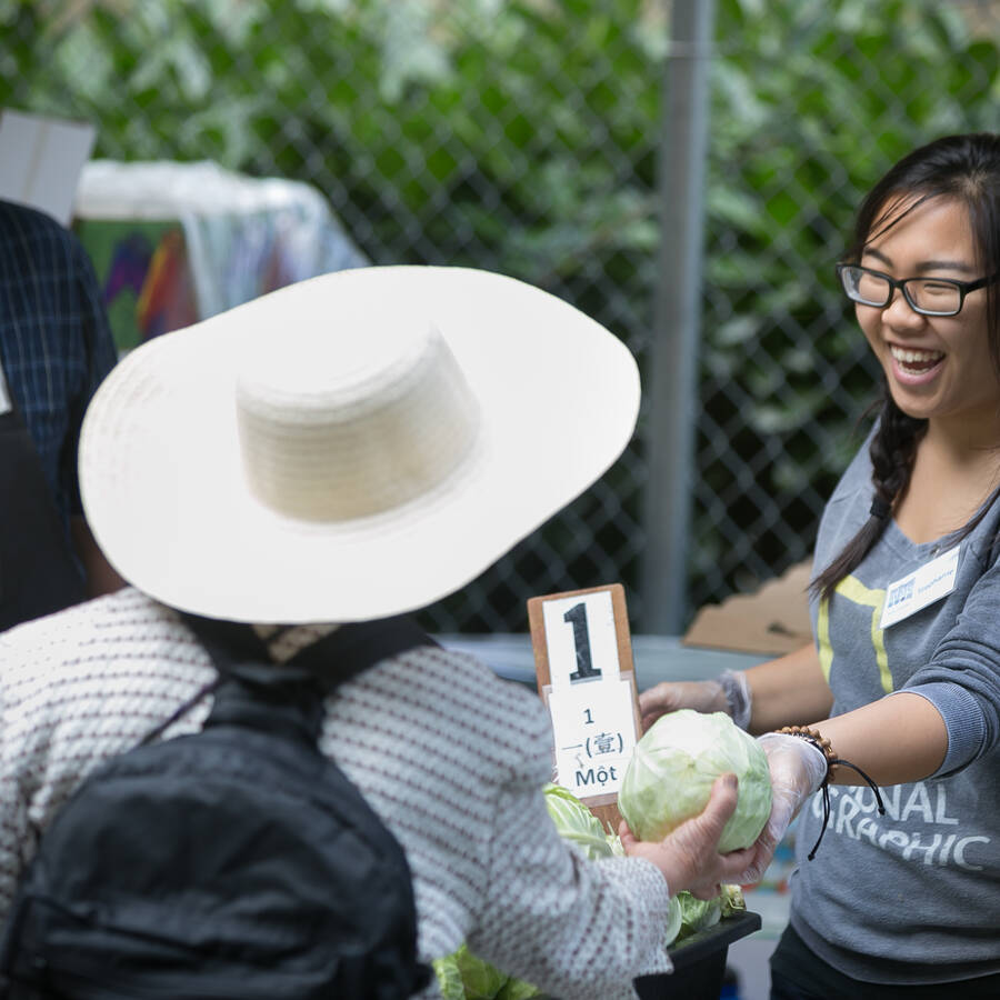 Smiling volunteer handing out food at a produce line in Vancouver, Washington for Northwest Harvest