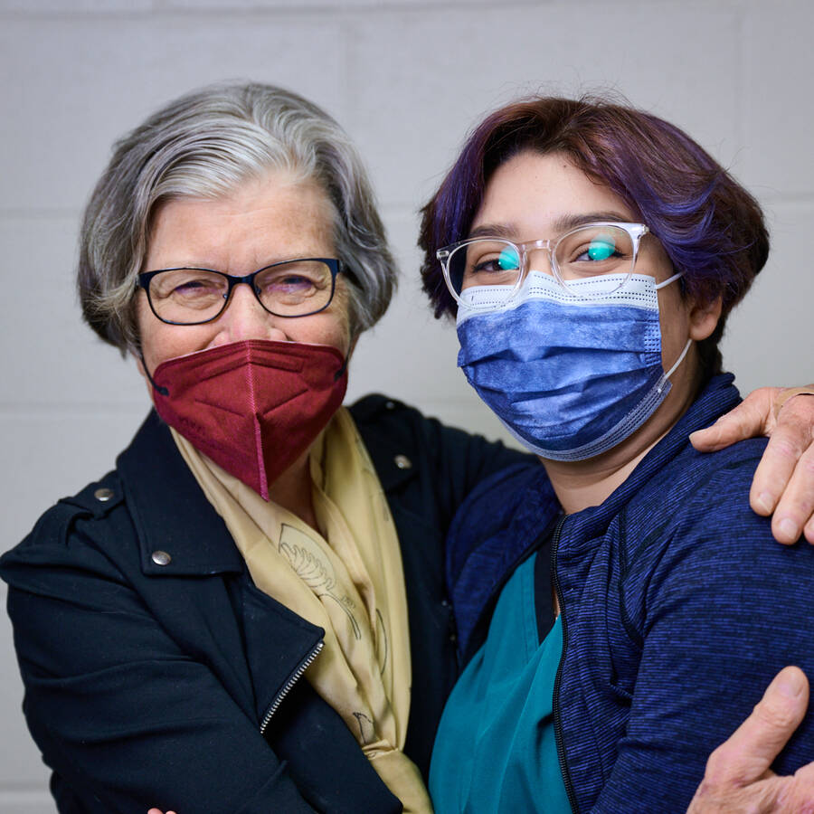 Two people wearing glasses and masks, with one person holding the other