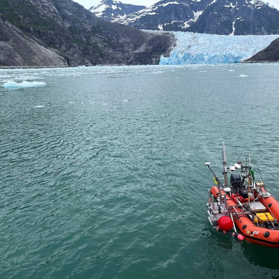 orange raft in icy waters with glaciers in the background
